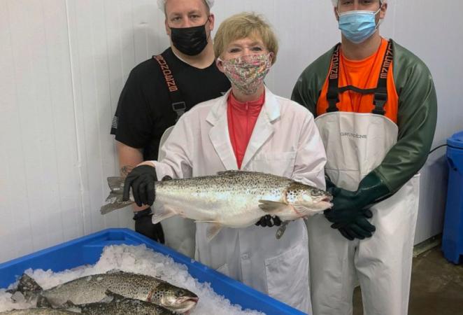 Mujer y dos hombres mostrando un Salmon